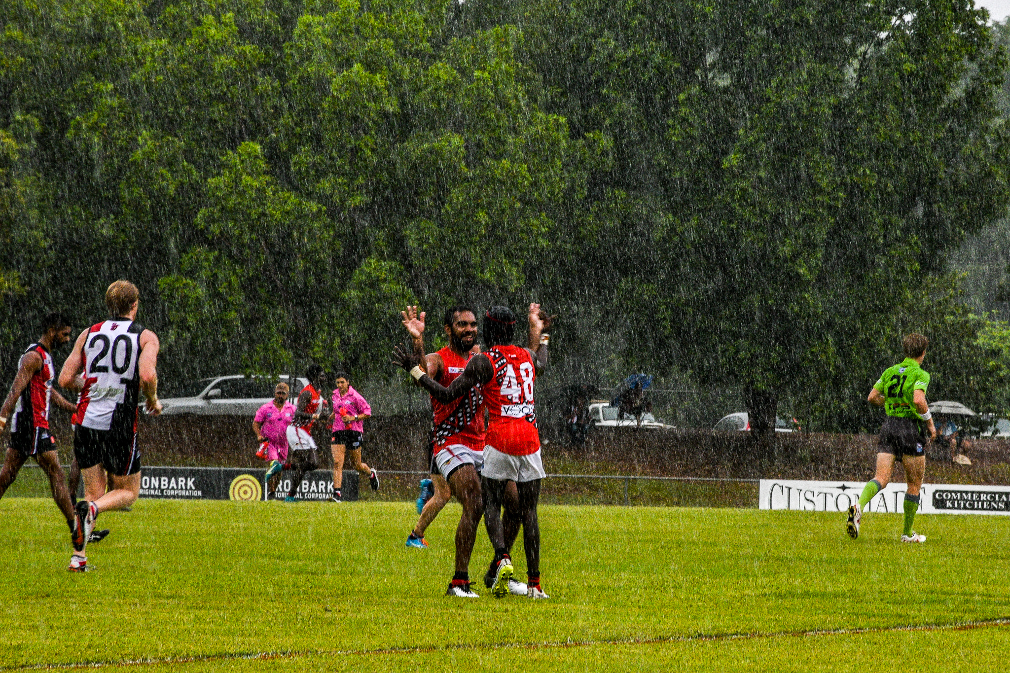 Yolgnu man Nathan Djerrkura – who played 25 games for the Cats and the Dogs in the AFL – celebrates with Harley Puruntatameri (number 48) in the rain. Tiwi Bombers v Southern Crocs, NTFL round 14, January 19, 2019.