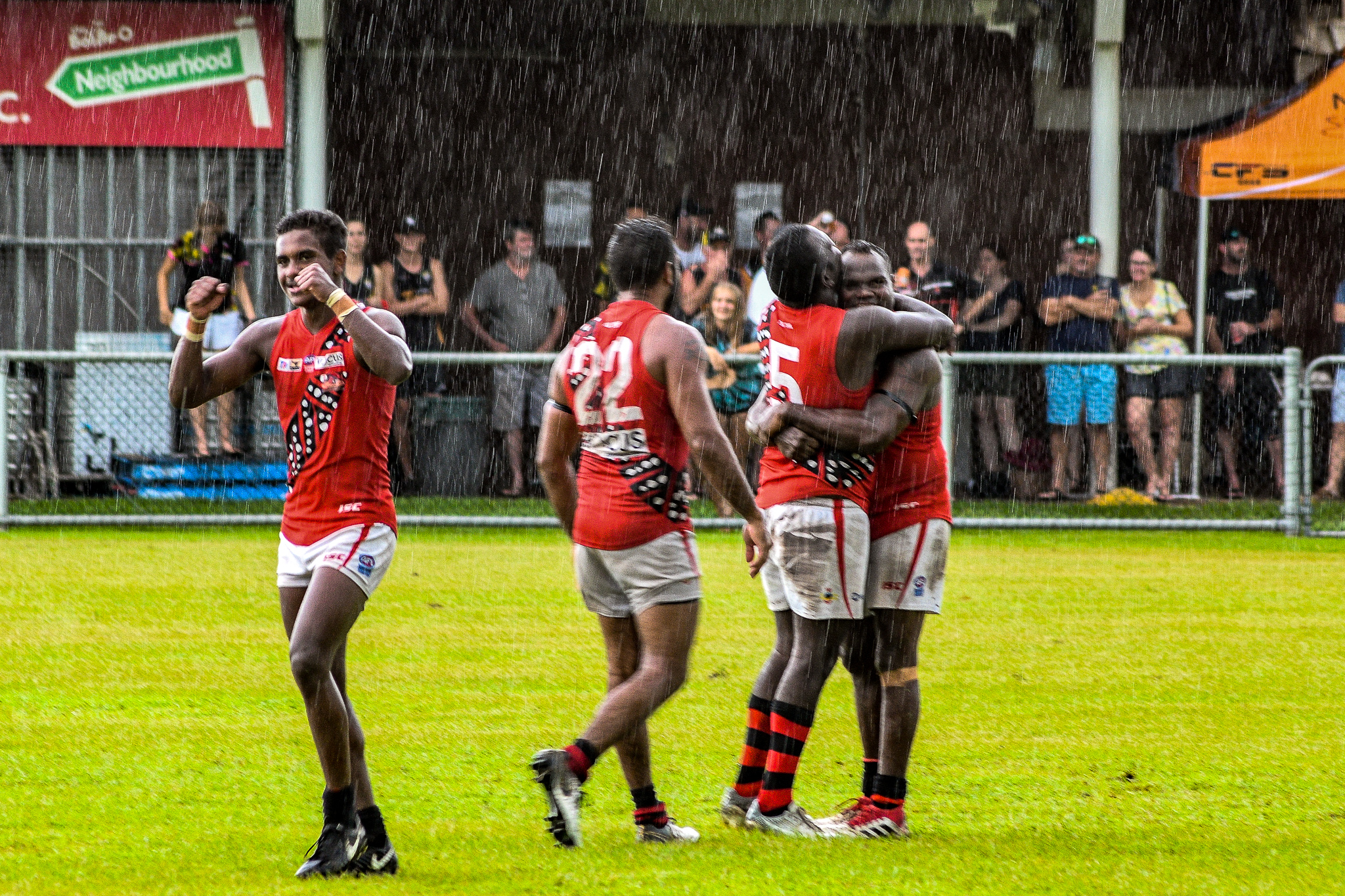 Jeffrey Simon Jnr punches the air, while Simon Munkara and Shane Tipuamantmirri embrace. Tiwi Bombers v Nightcliff Tigers, NTFL round 15, January 27, 2019.