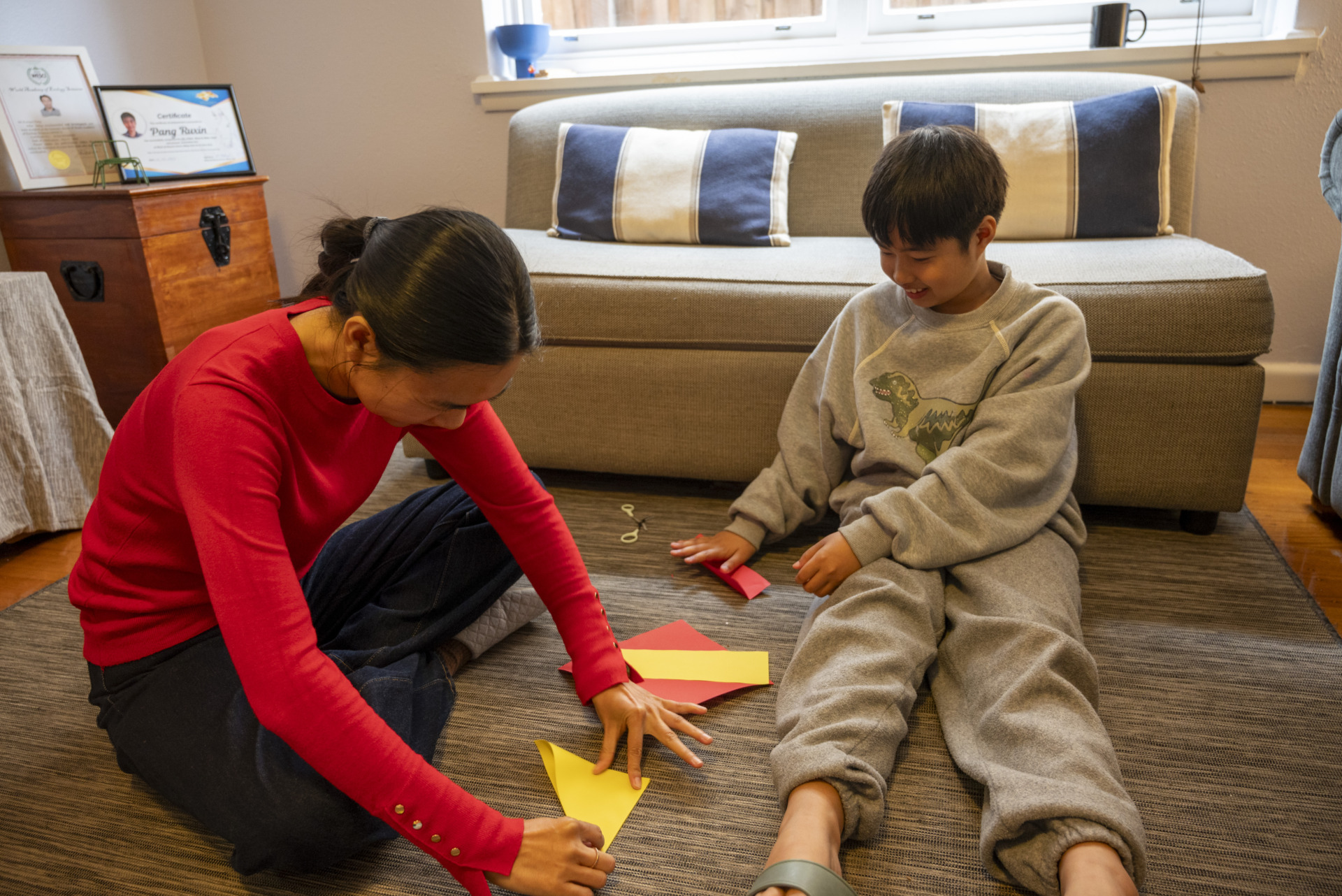 Ling and her son, Edward Pang, fold colourful paper in their living room. Ling, a former kindergarten teacher in China, is skilled at origami and paper cutting. She often does these activities with her son during their free time. Pang keeps his favourite creations in his room.