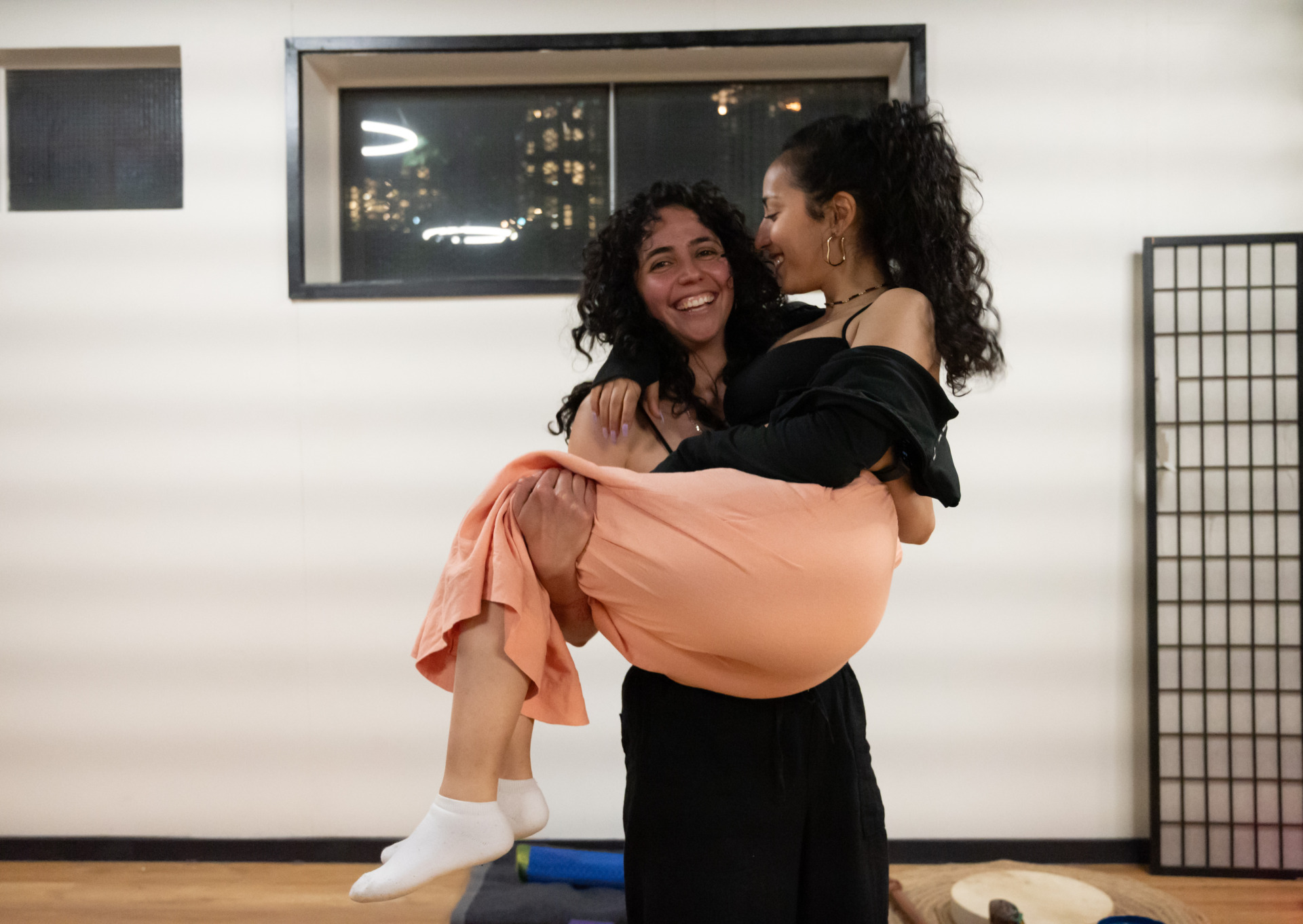 A photo of Ayat Alhakim, one of the Women&rsquo;s Circle members, with organiser Carolina Romero in the studio (216 York St, South Melbourne). Carolina is smiling as she lifts Ayat up. Ayat is Carolina&rsquo;s best friend and they have known each other since before the Women&rsquo;s Circle was established. Ayat supported Carolina through the toughest moments after their immigration to Australia, assisting her in organising many events.