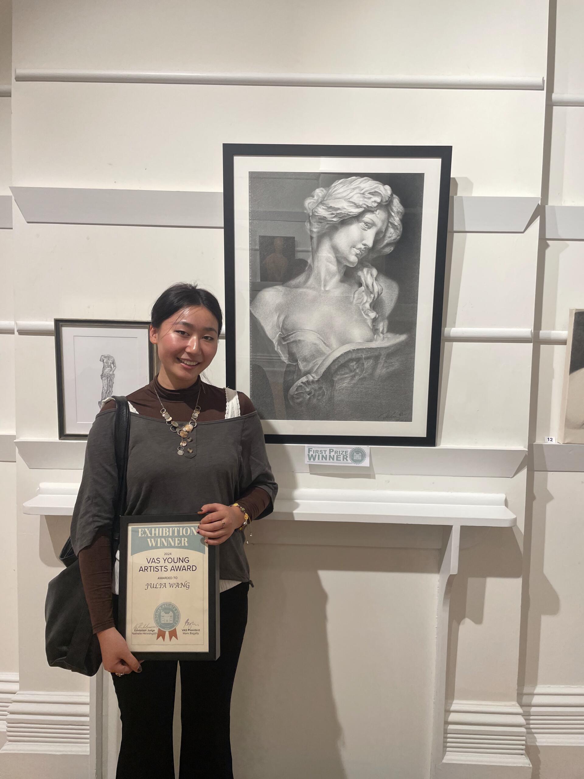 Julia Wang stands next to the drawing that won her first prize in the Victorian Artists Society Young Artists Award in 2024. Photo: Charlotte Walkling