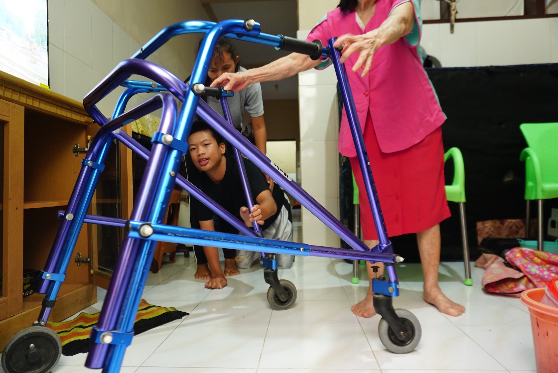 Jonathan crawls to reach his posterior walker in his preparation for a walk at their home in Surabaya, Indonesia. Photo: Kristian Oka Prasetyadi