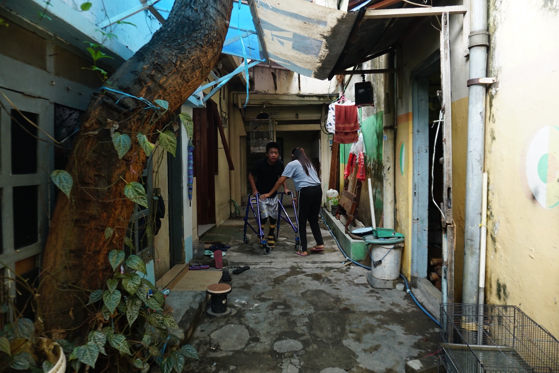 Jonathan steps outside of his house with the help from Ayung Tarunawati, his carer, to go for a walk in the neighbourhood of Dinoyo in Surabaya, Indonesia. Photo: Kristian Oka Prasetyadi