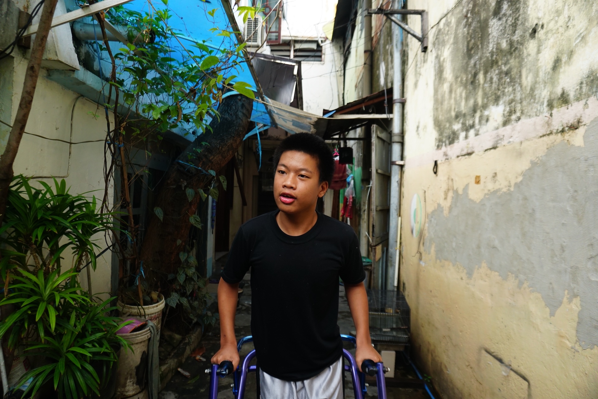 Jonathan, 14, steps outside of his house to go for a walk in the neighbourhood of Dinoyo in Surabaya, Indonesia.