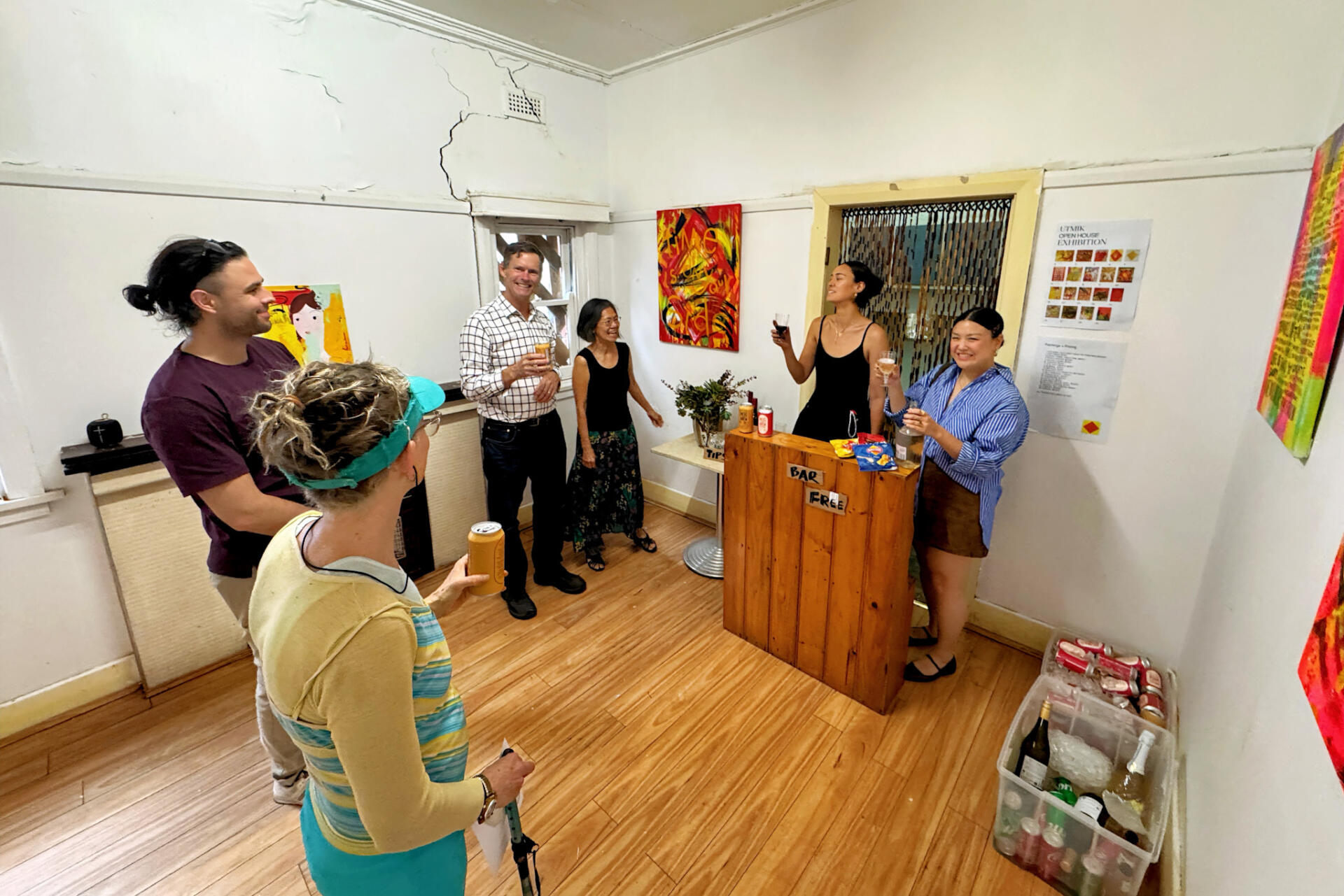 One of the artists in Gallery FiveNinetySix, during an exhibition hosted by The Op Shop, displays and sells their artwork as guests enjoy complimentary drinks.