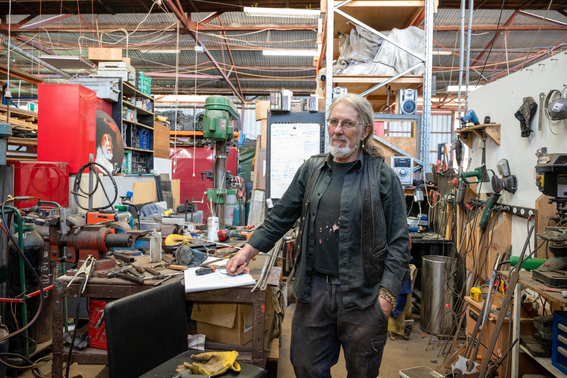 Swordsmith, Tim Harris, in the front section of his workspace at FML, where the surrounding tools and notes reflect his creative thinking and workflow.