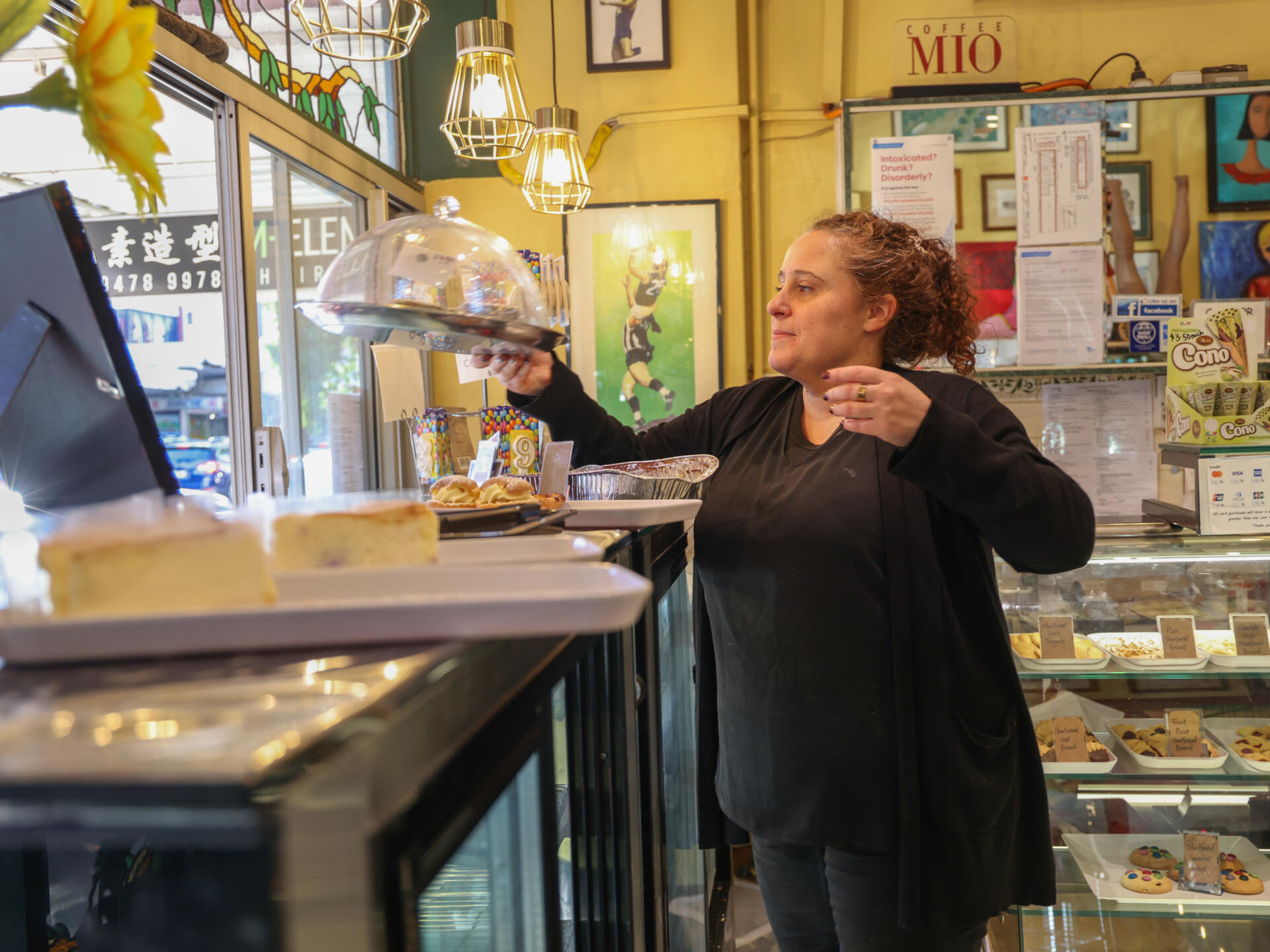 Nadia hands a dessert to a customer through the window.