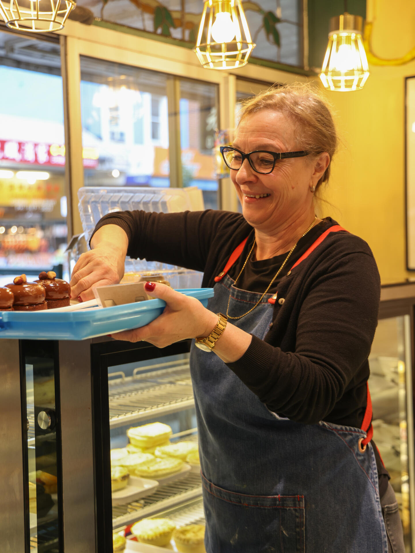 Elena, a staff member, arranges pastries in the display case.