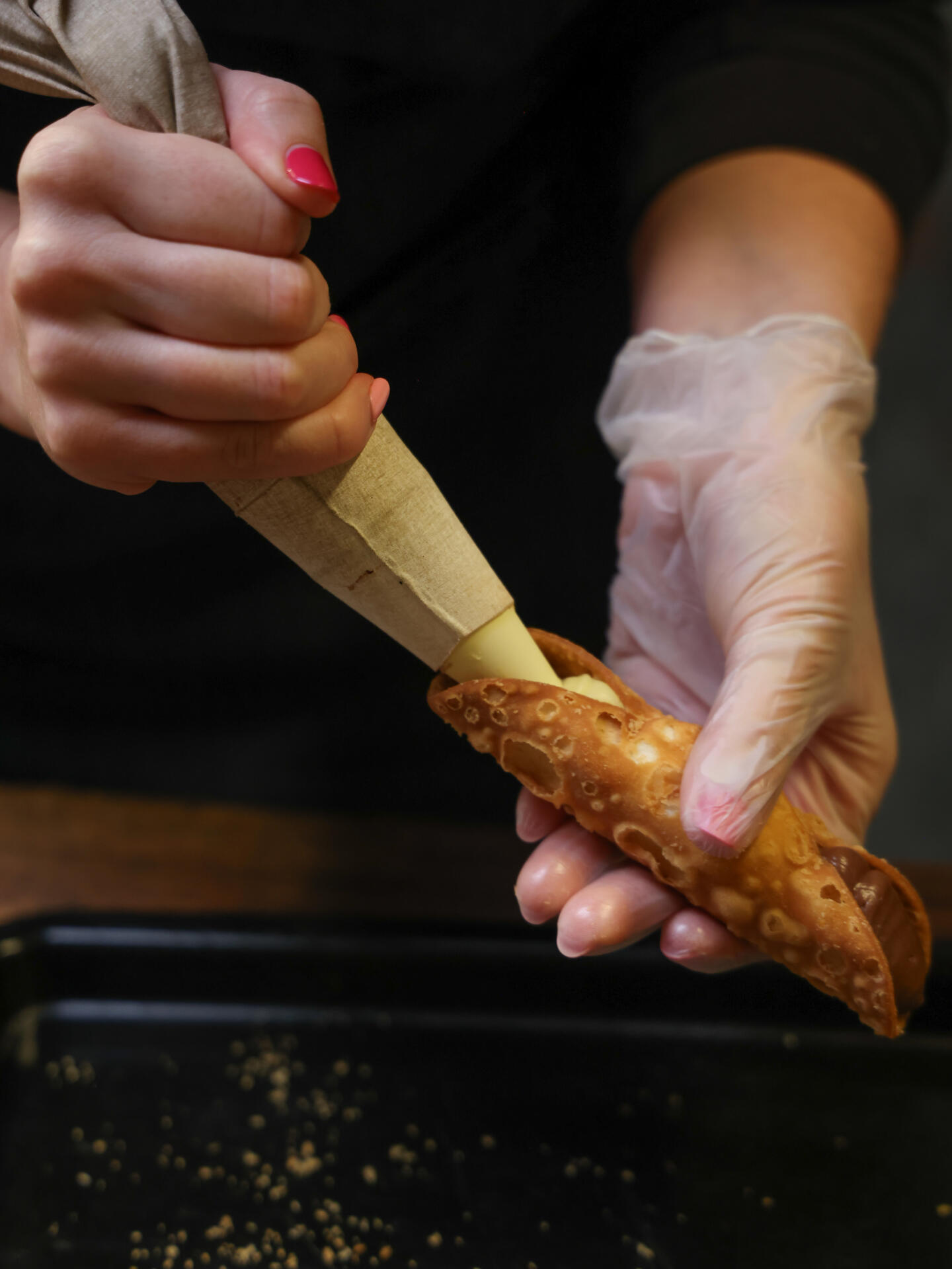 Fresh cannoli being filled with cream in the kitchen.