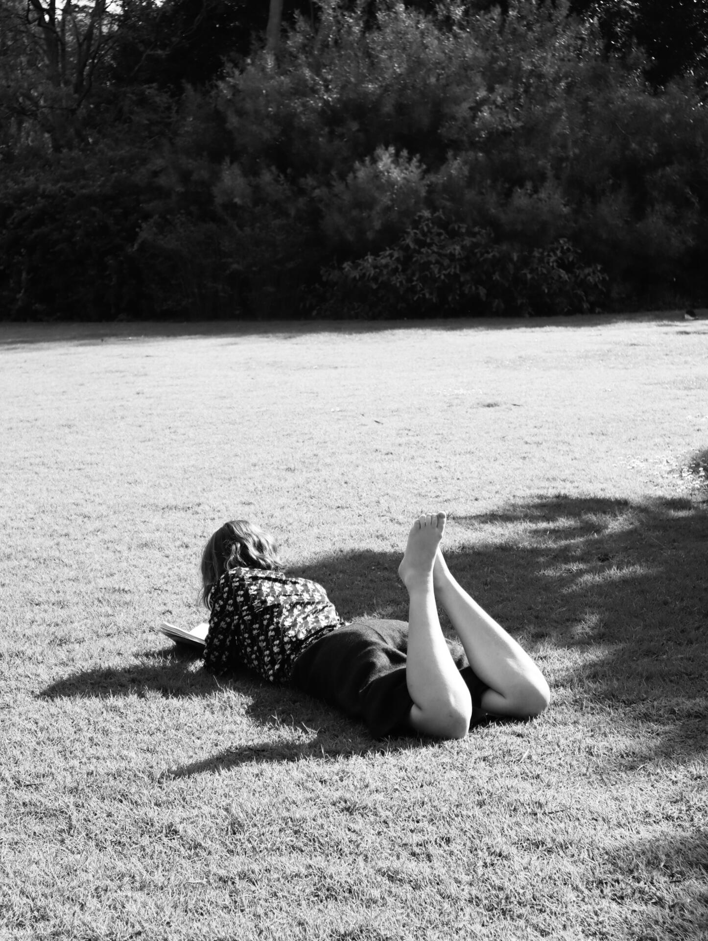 A woman reads while lying on the grass