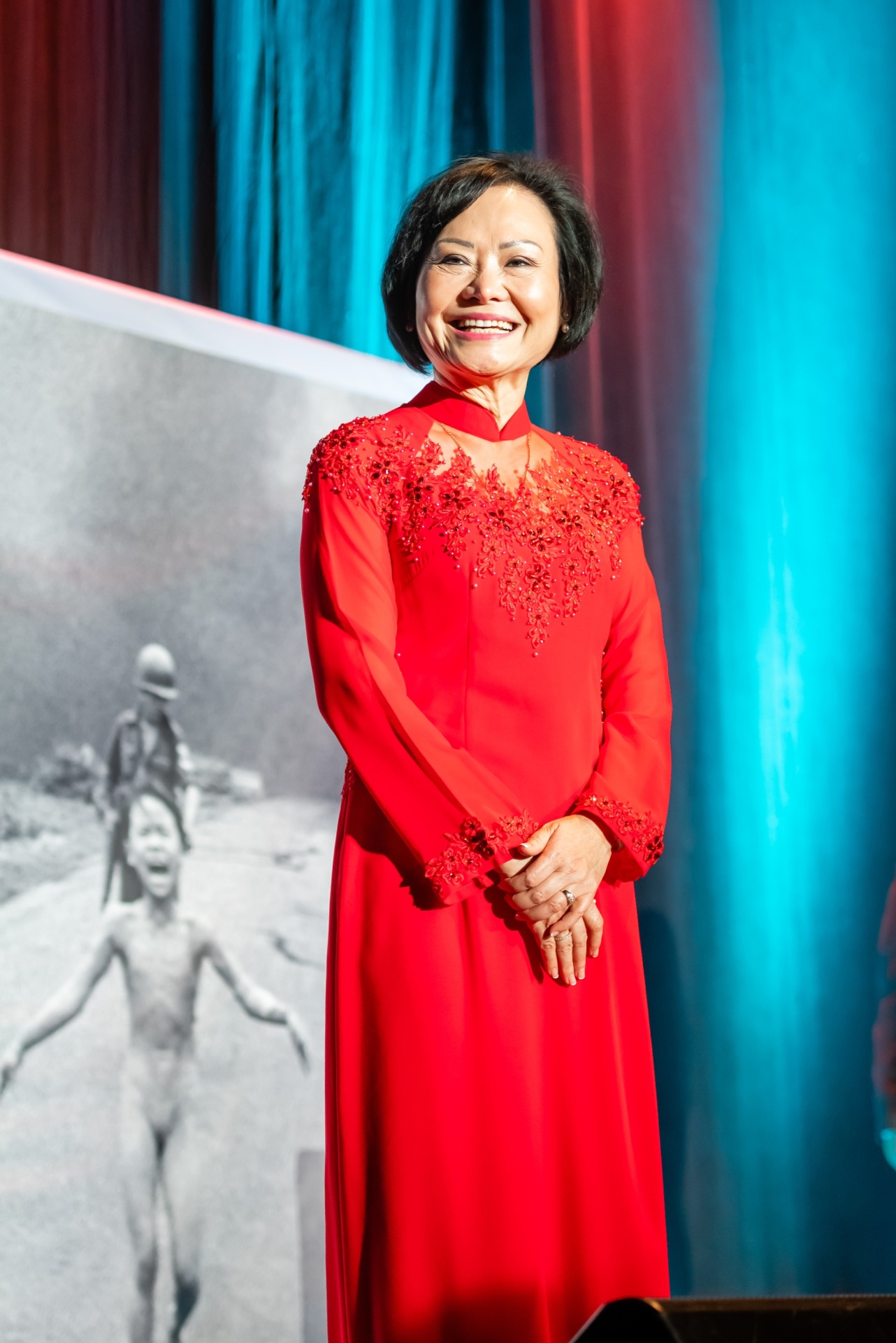 Phan Thị Kim Ph&uacute;c standing alongside &lsquo;The Terror of War&rsquo;, the image that has defined much of her life. Photo: Stephanie Brown, @stefbrownphoto.
