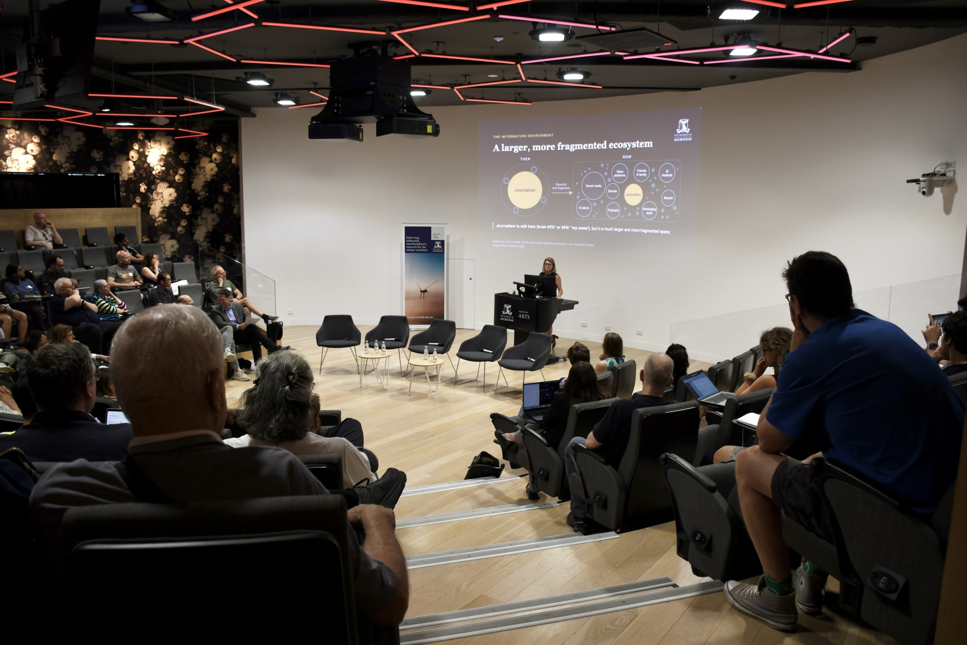 Professor Andrea Carson presents early research on how data centres are discussed on Facebook and Instagram to a full Forum Theatre in Parkville. Photo by Preeshita Shah